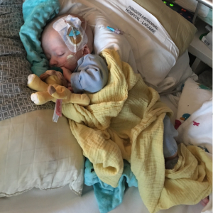 Lauren Throop's son lies asleep in a hospital bed, with a large IV coming from his head.