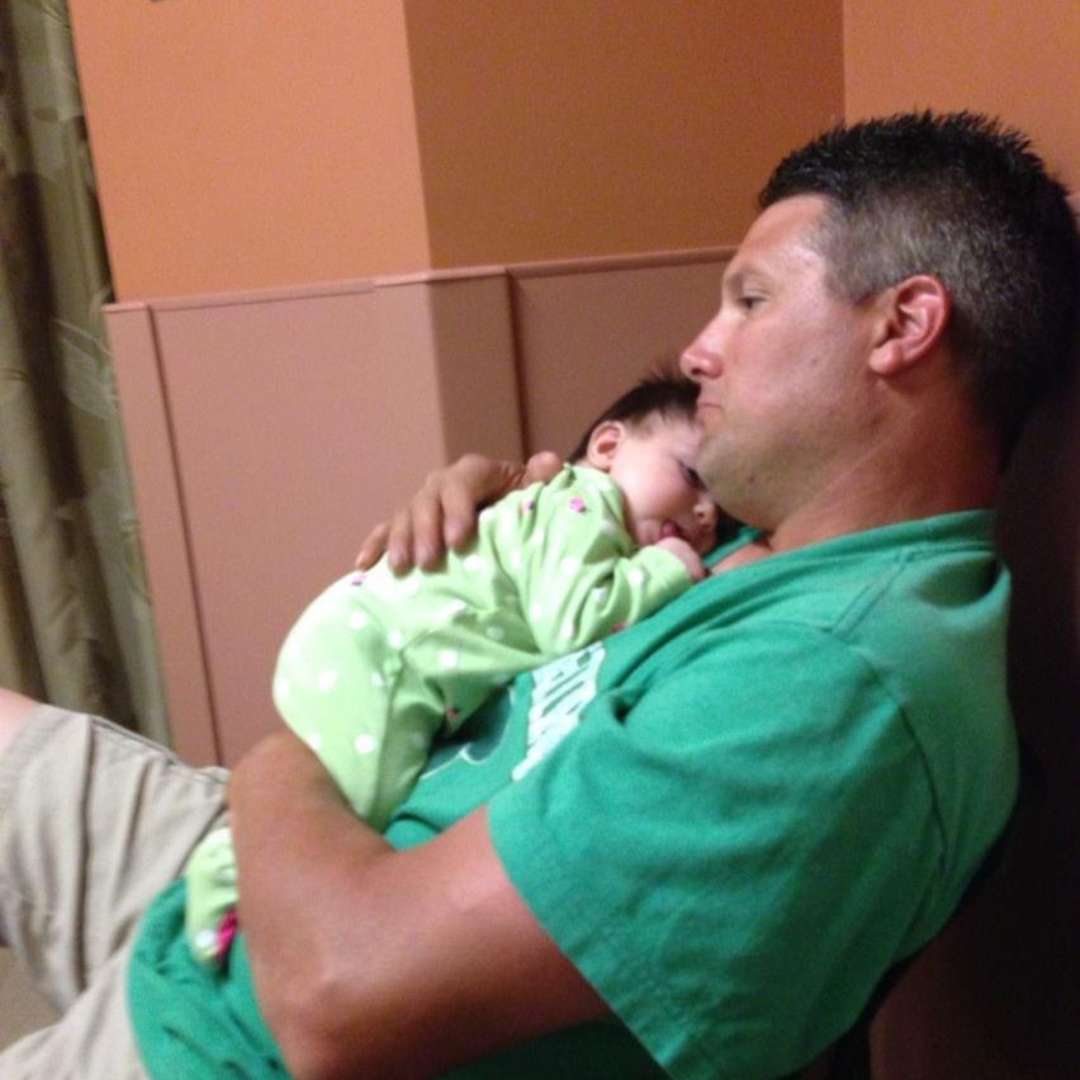 Mr. Nicotra sits in a hospital chair and holds his baby girl.